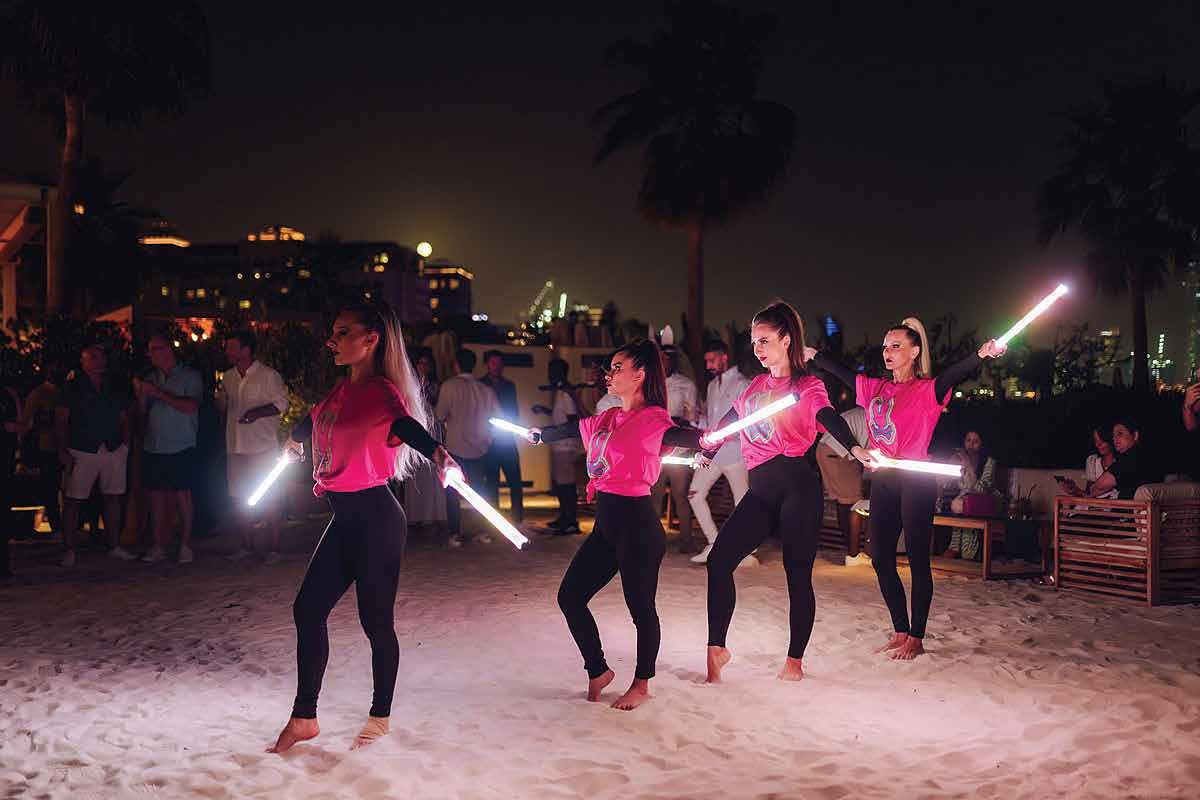 LED dancers performing on the beach at the Psycho Bunny night