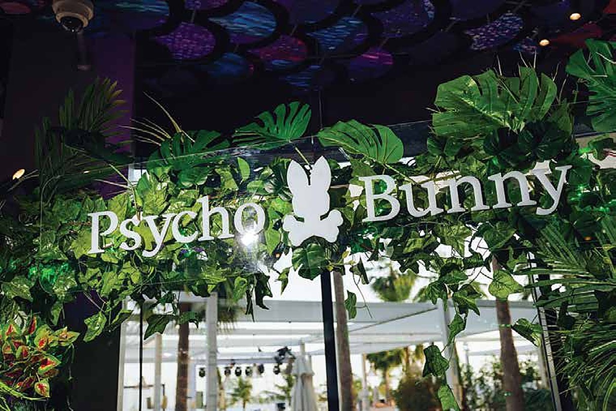 Psycho Bunny sign framed by tropical leaves